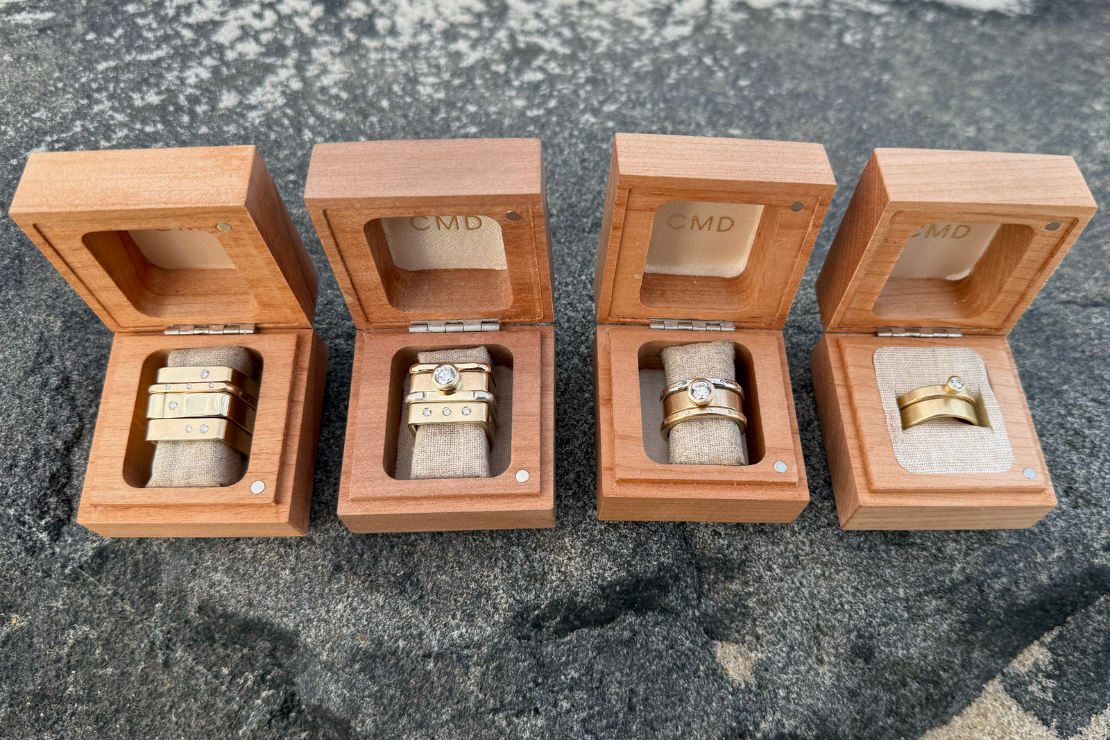 CMD mixed-metal diamond ring stacks displayed in four wooden jewelry boxes