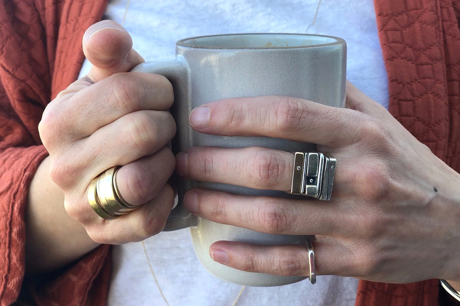 Colleen Mauer holding a cup of coffee while wearing stacked CMD rings
