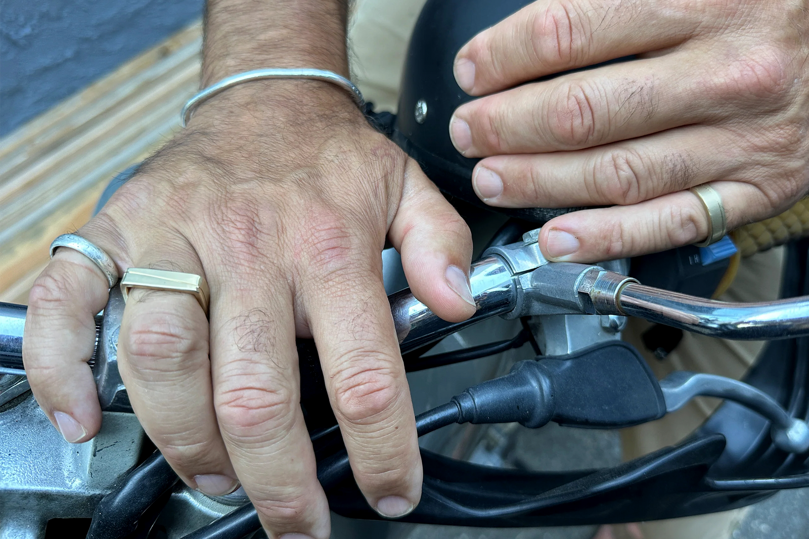 man's hands wearing the 14k Gold Line Ring and other CMD rings on a motorcycle