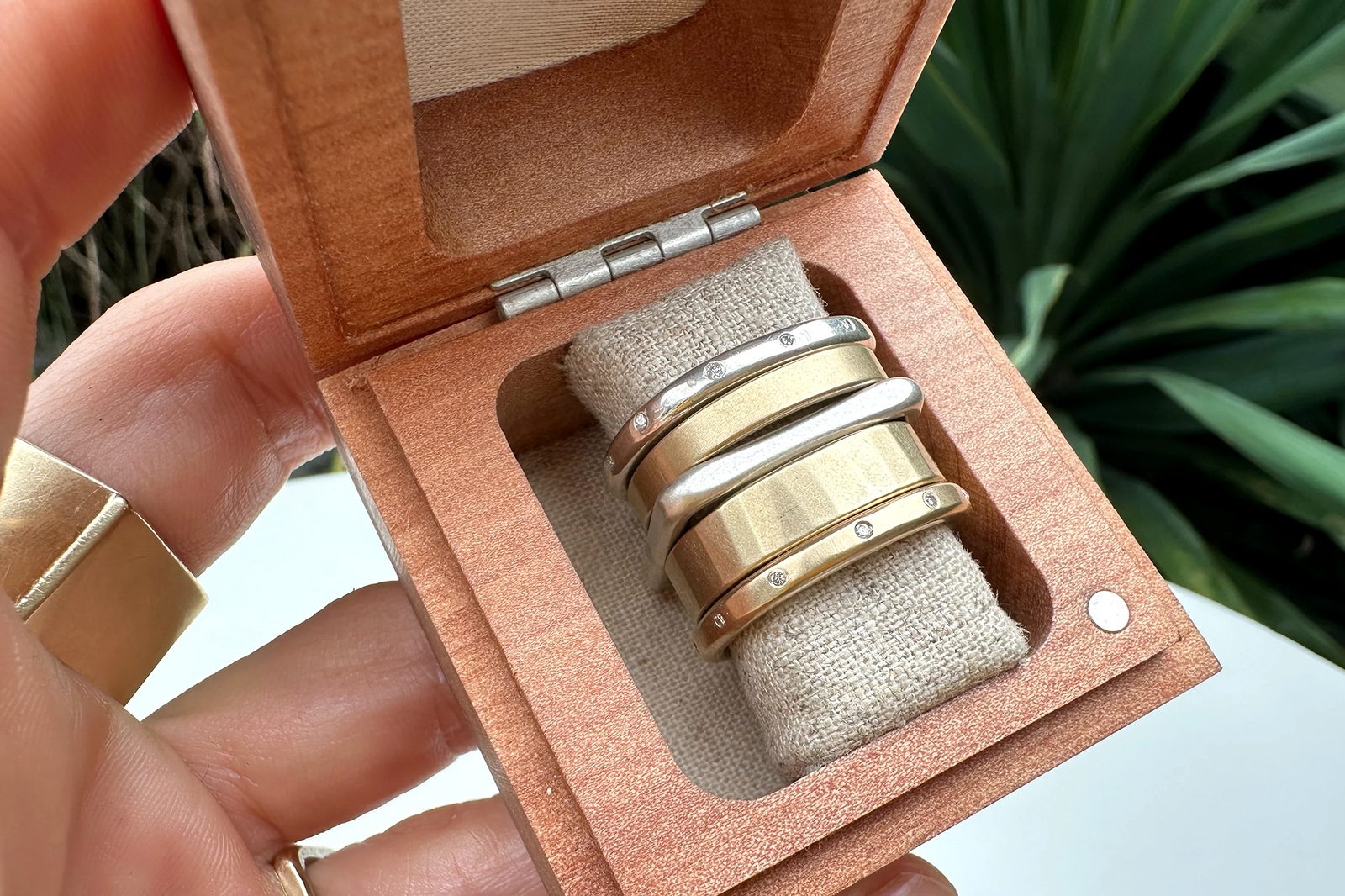 Mixed-metal CMD ring stack featuring round and square sterling silver, gold and diamond bands displayed in a jewelry box.